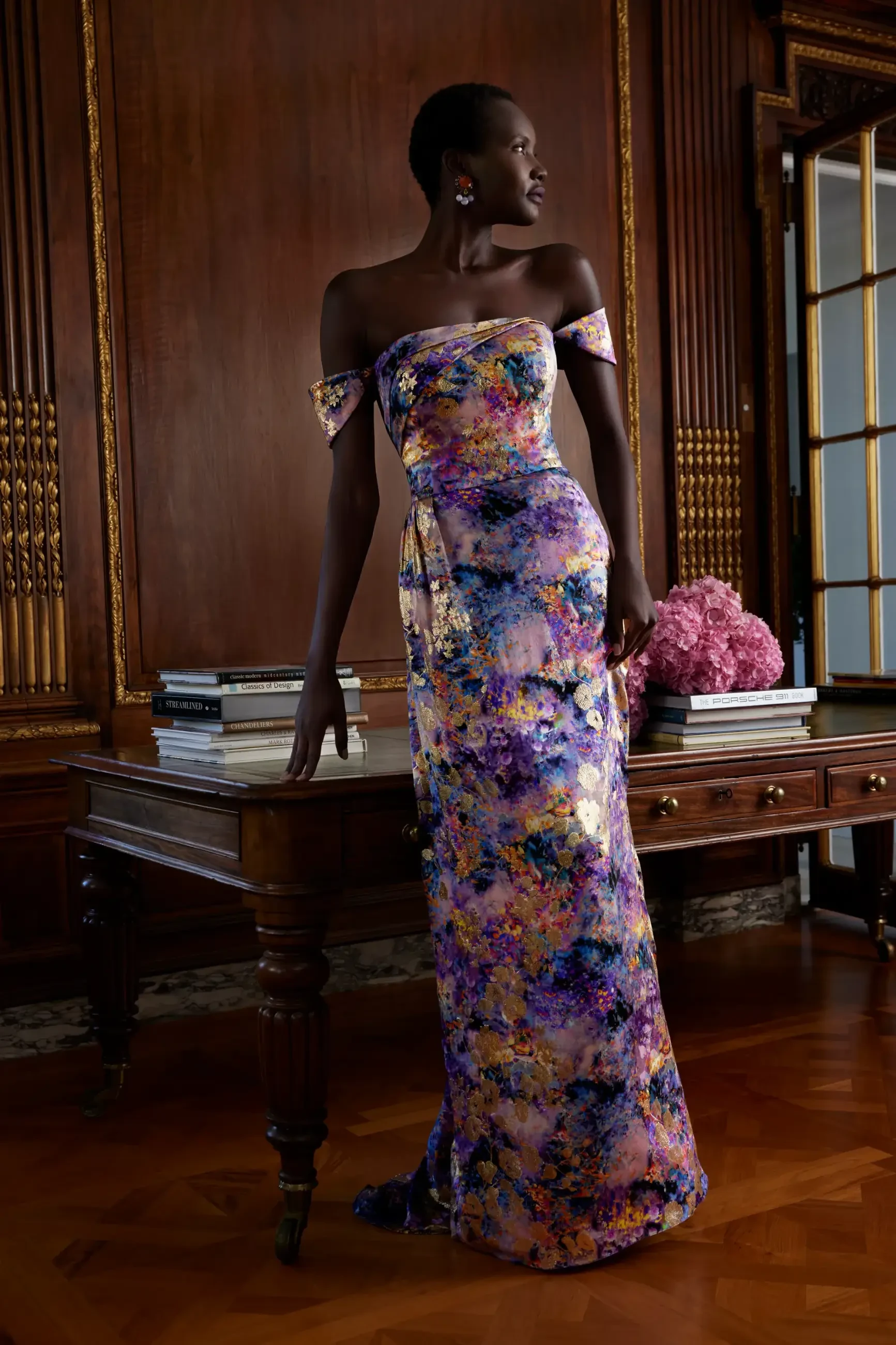Model is wearing a silky gold floral off the shoulder evening gown by sareh nouri