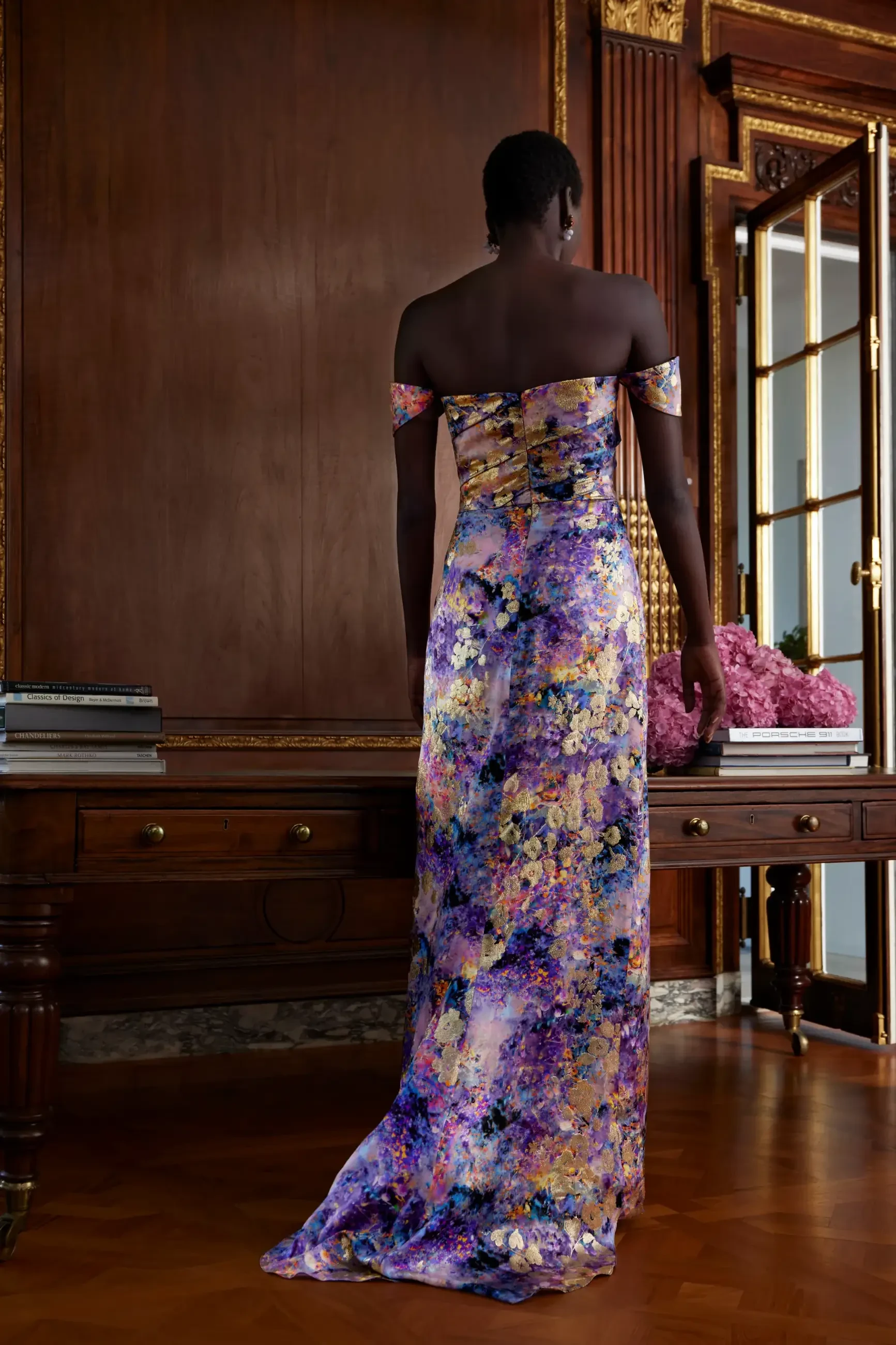 Model is wearing a silky gold floral off the shoulder evening gown by sareh nouri