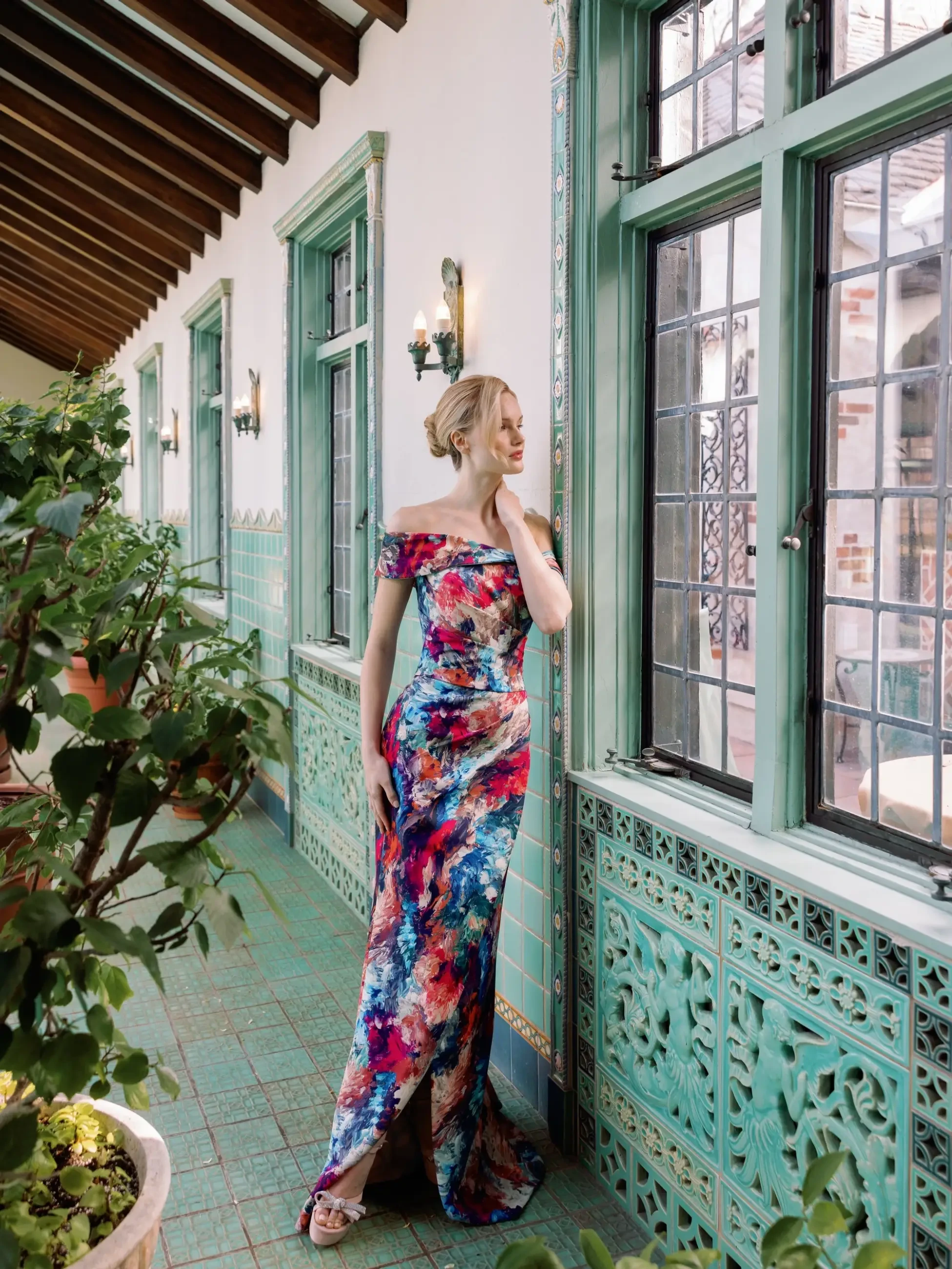 Model is wearing a slim evening gown in printed reds and blues by sareh nouri