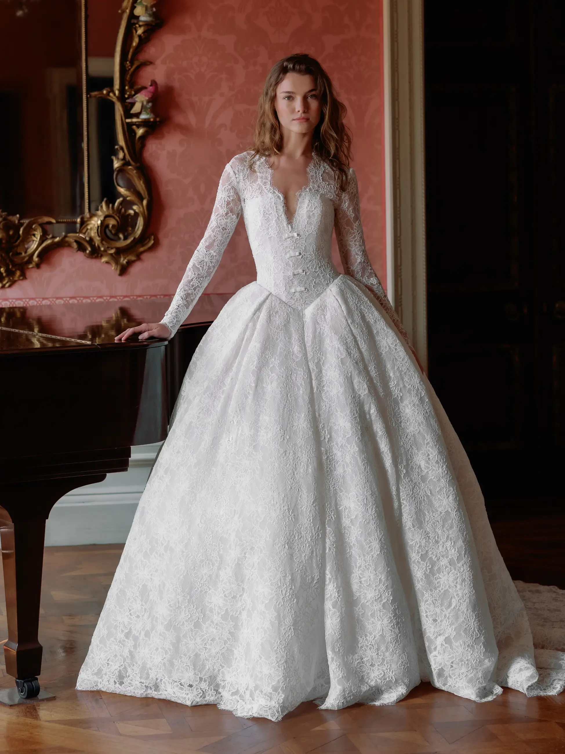 Model is wearing a ball gown wedding dress with a v-neckline and long sleeves