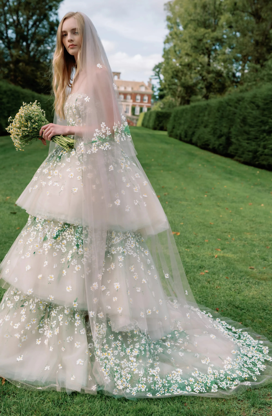 Model is wearing a three tiered ball gown wedding dress with a detachable underskirt that converts the gown into a mini dress