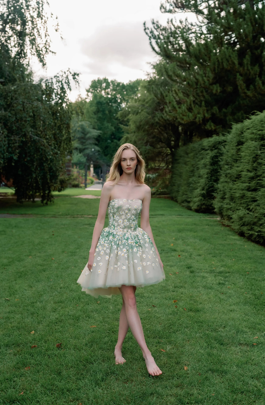 Model is wearing a three tiered ball gown wedding dress with a detachable underskirt that converts the gown into a mini dress