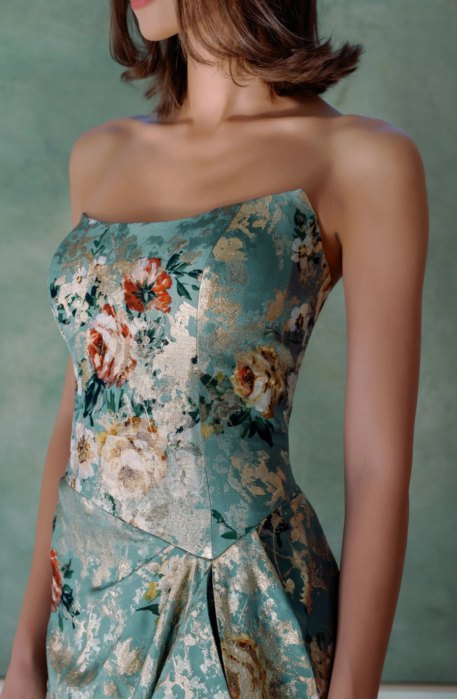 A close-up of a woman's upper body wearing a strapless floral dress.