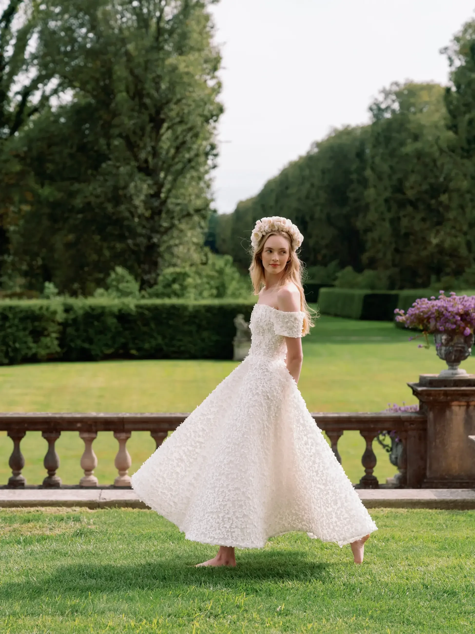 Model is wearing an off the shoulder a-line tea length wedding dress