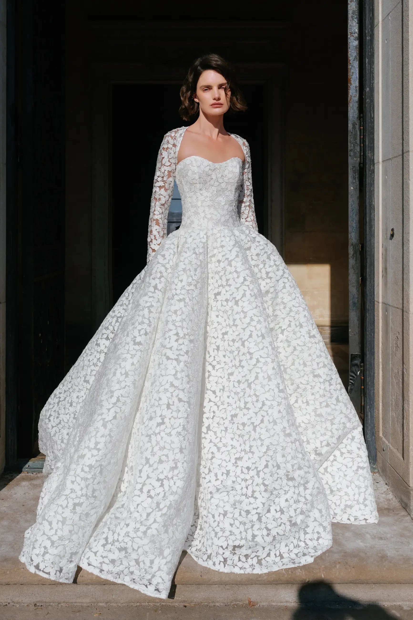 model is wearing a lace long sleeve ball gown wedding dress