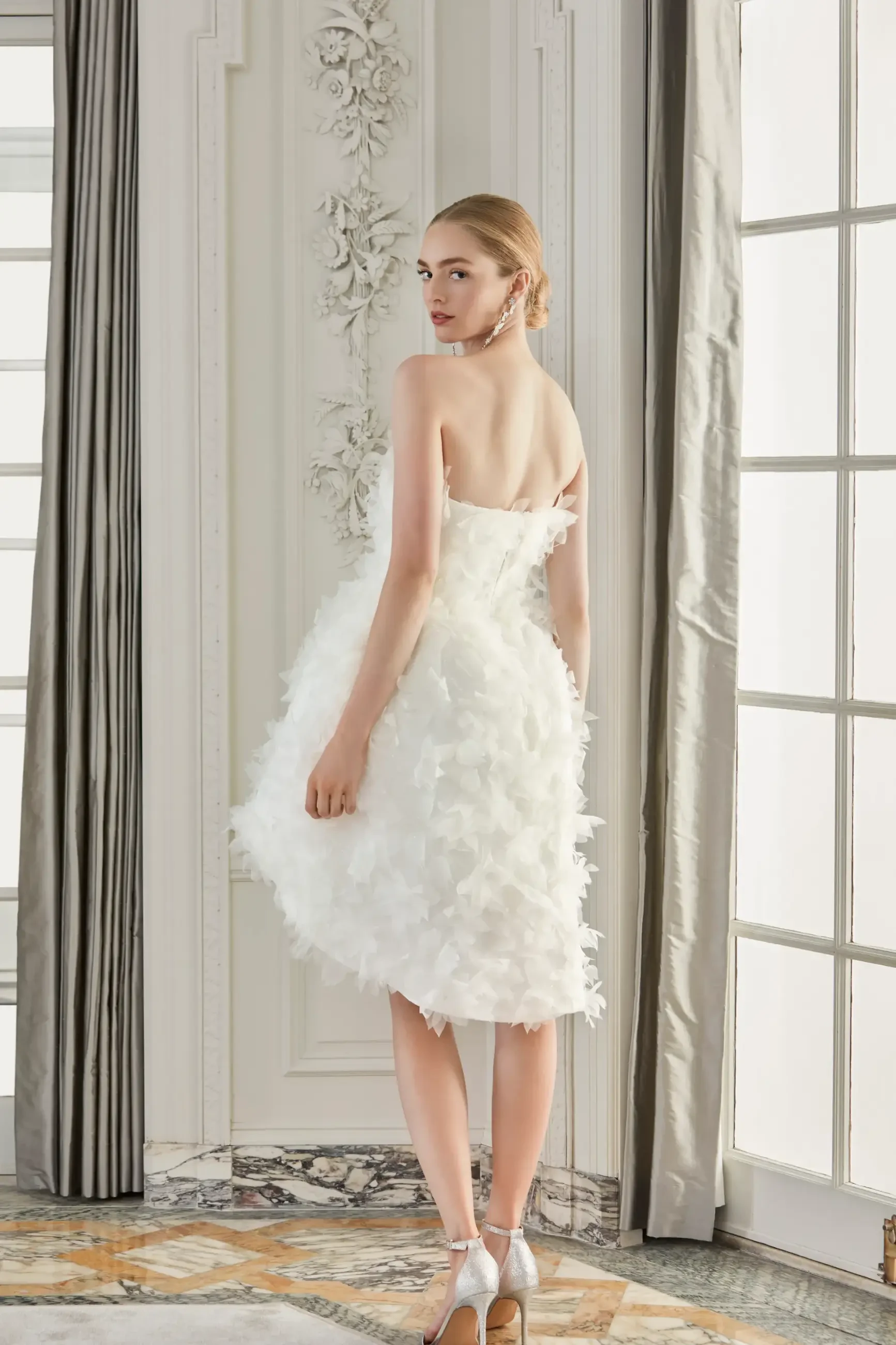 model wears a strapless mini floral wedding dress