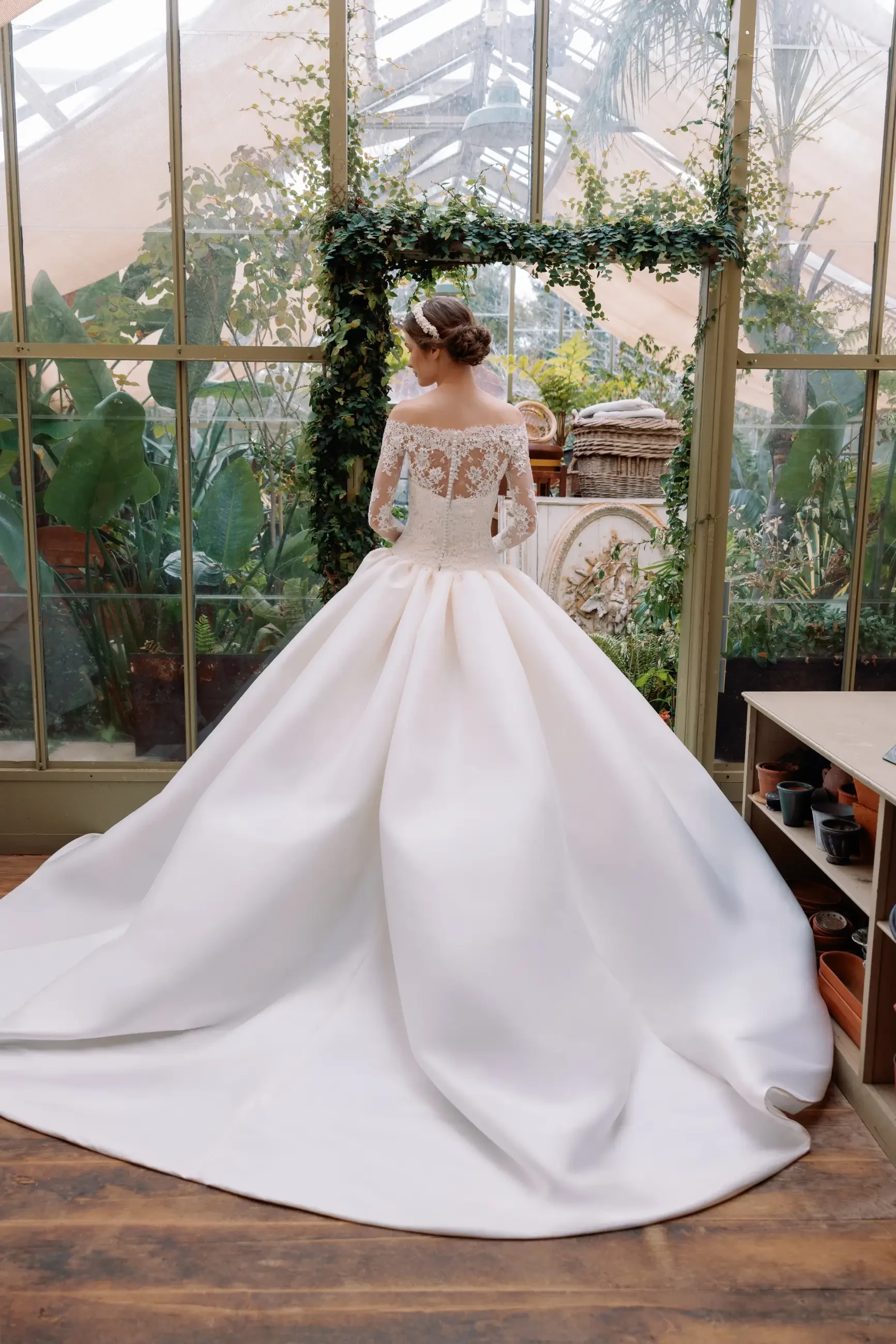 Model is wearing a lace and mikado drop waist ball gown wedding dress