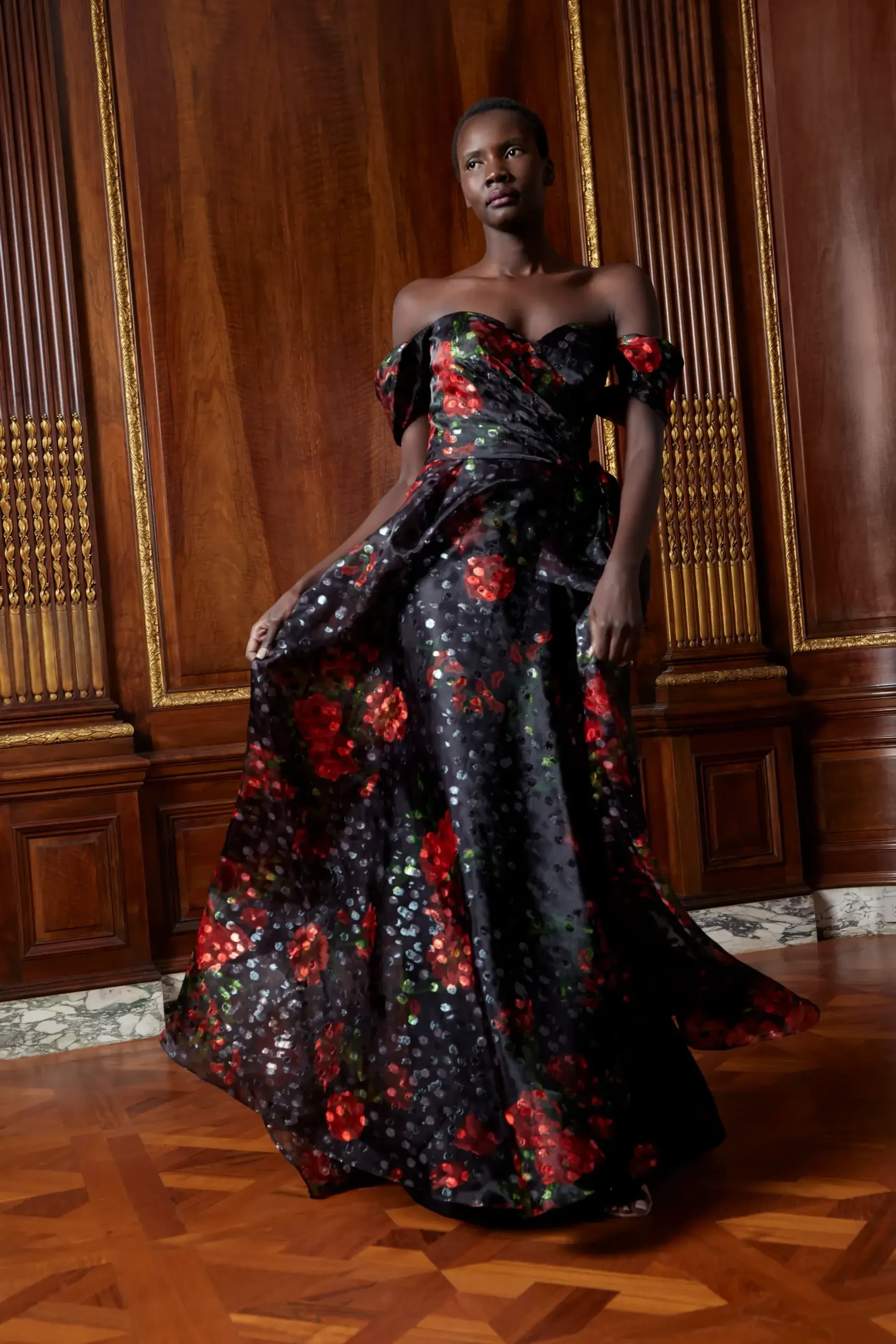 Model is wearing an off the shoulder floral print A-line evening gown by sareh nouri