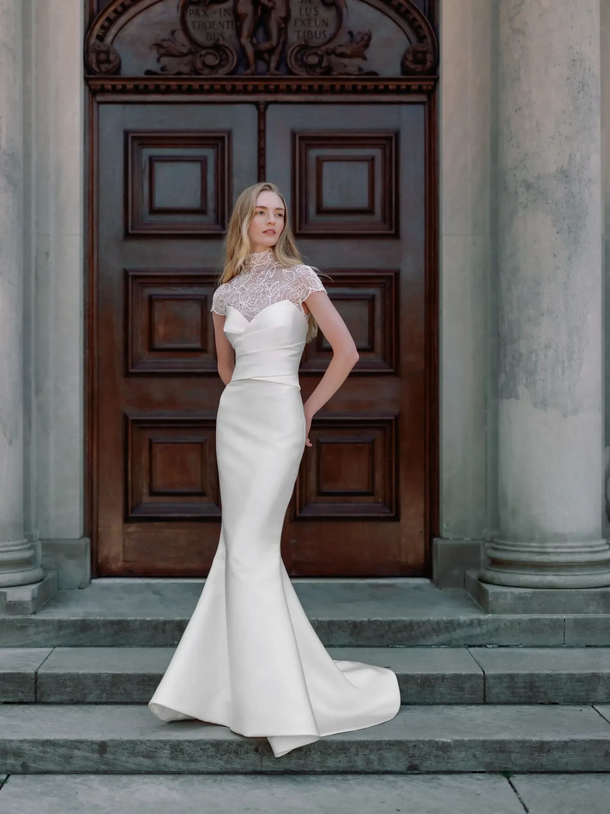 model is wearing a high neck cap sleeve fit and flare wedding dress
