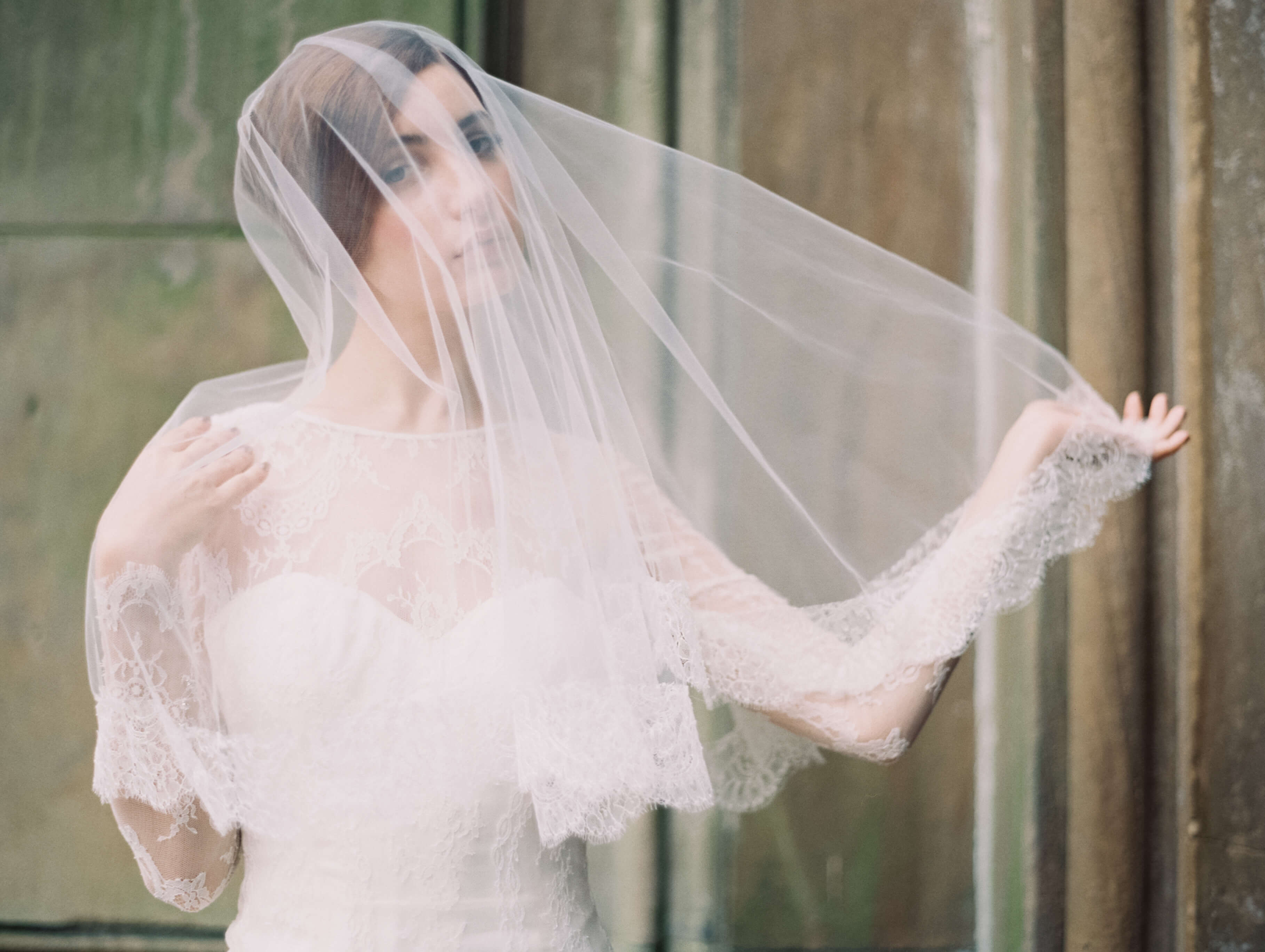 Photo of the model wearing bridal gown near the wall under the veil